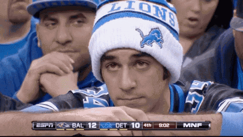 a man wearing a lions hat sits in a stadium