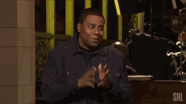 a man clapping in front of a snl sign