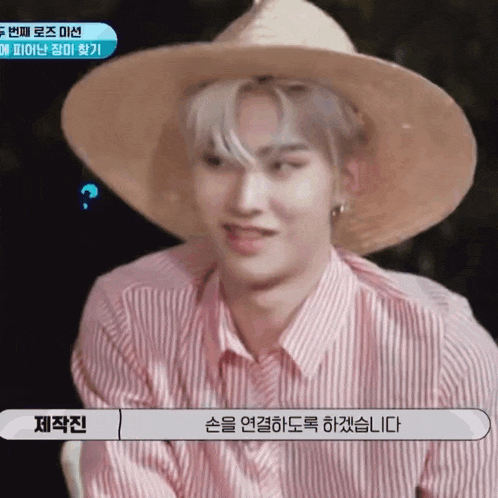 a man wearing a straw hat and a pink striped shirt is talking in a foreign language