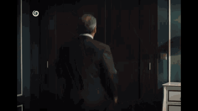 a man in a suit and a woman in a fur vest are walking through a doorway