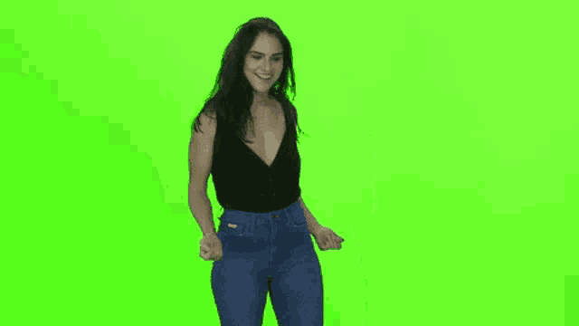 a woman is dancing in front of a green screen .
