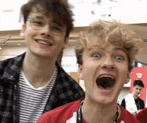 two young men are standing next to each other and one of them is making a funny face .