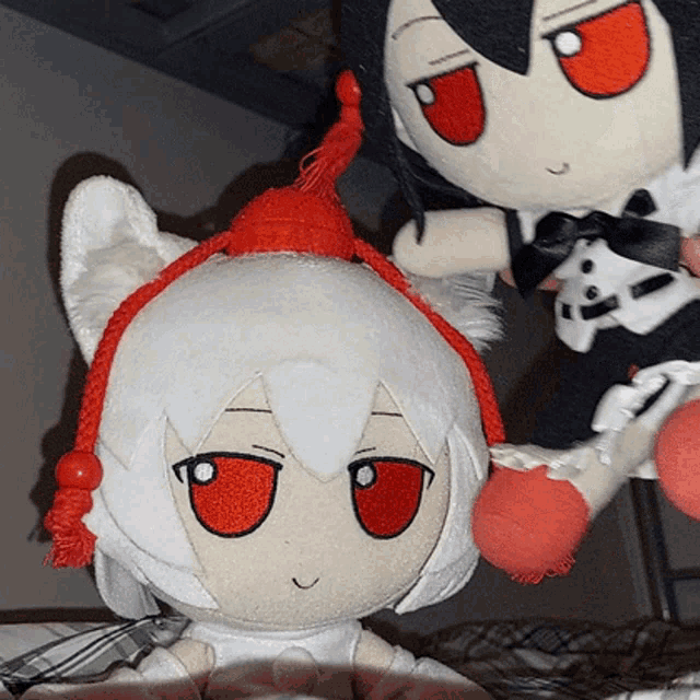 a white stuffed animal with red eyes is next to another stuffed animal