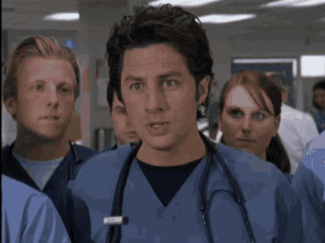 a man with a stethoscope around his neck stands in a hospital
