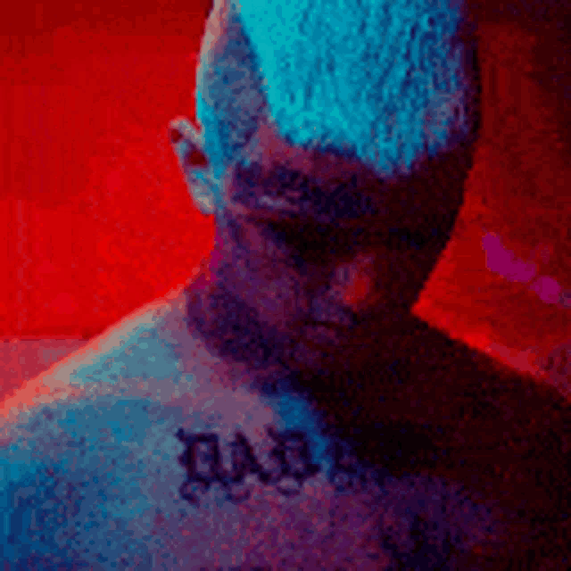 a man with a mohawk and a tattoo on his chest is standing in front of a red background .