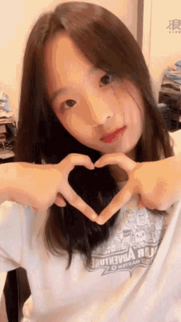a girl making a heart shape with her hands while wearing a t-shirt that says " orbital "