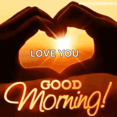 a person is making a heart shape with their hands with the sun behind them .