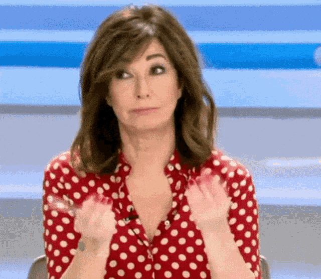 a woman wearing a red polka dot shirt is making a face