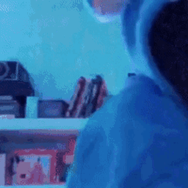 a person wearing a blue hoodie with ears is standing in front of a bookshelf .