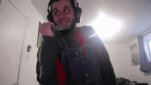 a man wearing overalls and headphones is smiling