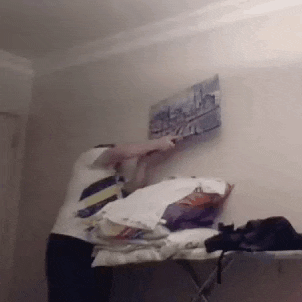 a man is ironing clothes on an ironing board in a room .