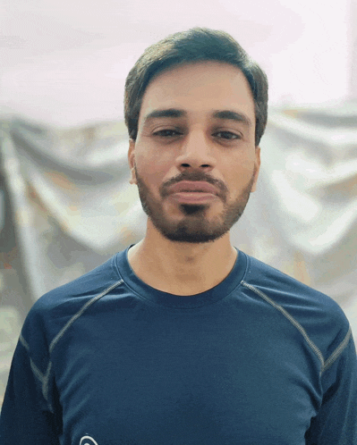 a man with a beard is wearing a blue shirt with the letter s on it