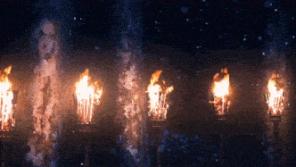 a row of lit torches are lined up in a dark room