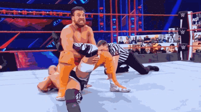 a wrestling match is underway with a referee and a w logo in the background