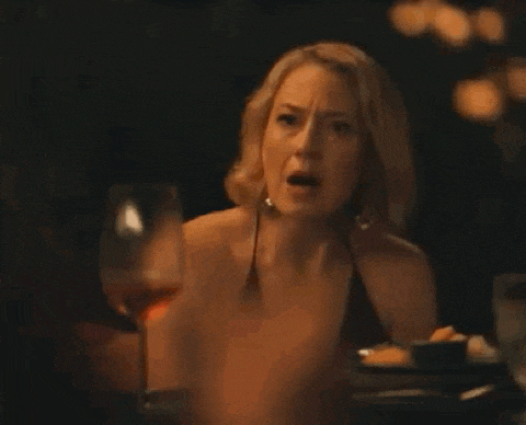 a woman is sitting at a table with a glass of wine and a plate of food .