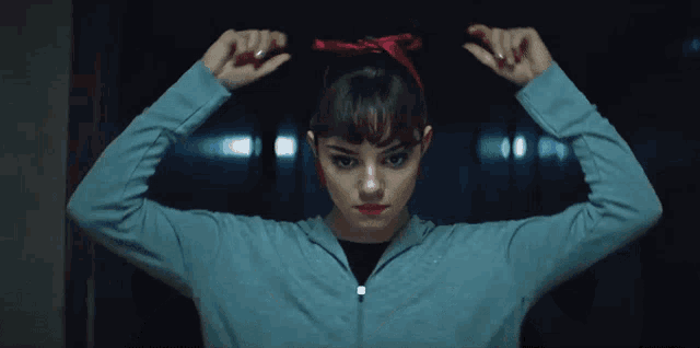 a woman in a blue hoodie is flexing her muscles