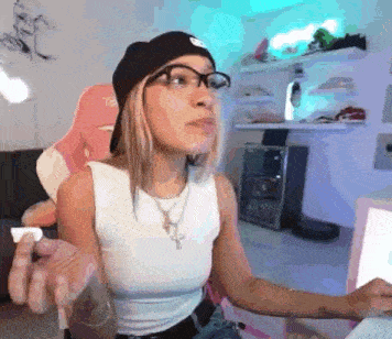 a woman wearing glasses and a beanie is sitting in a chair in a room .