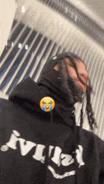 a man with dreadlocks wearing a black hoodie that says ' amiri ' on it
