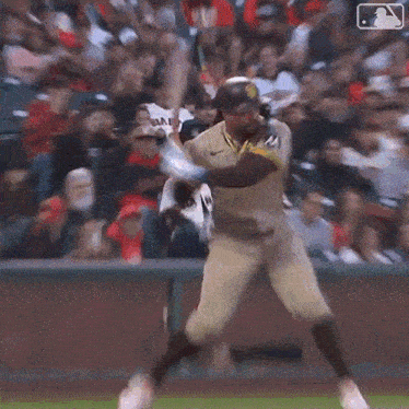 a baseball player is swinging at a ball while a crowd watches .