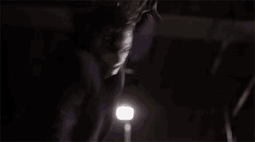 the joker is wearing a purple suit and tie and is holding a knife in his hand .