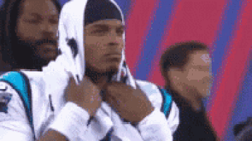 a man wearing a hooded sweatshirt is sitting in a stadium .