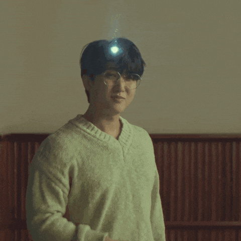 a young man wearing glasses and a sweater has a light on his head .