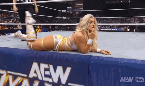 a woman is laying on the floor in a wrestling ring with a sign that says aew