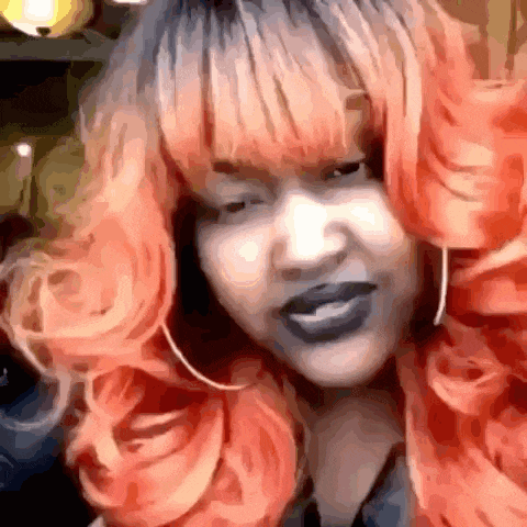 a woman with long red hair and hoop earrings is smiling and looking at the camera .