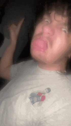 a blurry picture of a man with his tongue out wearing a white shirt