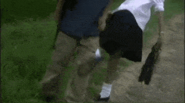 a man and a woman are walking down a road . the woman is wearing a skirt .