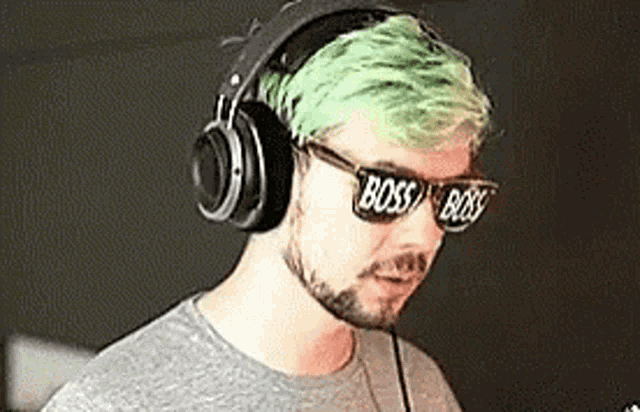a man with green hair and a beard wearing headphones and sunglasses with the word boss on them .