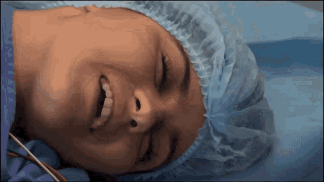 a woman in a surgical cap and gown is smiling with her eyes closed