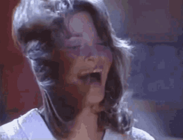 a woman is laughing with her hair blowing in the wind .