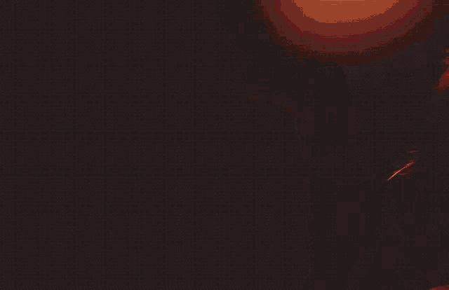 a woman in a red crop top and pants is standing in a dark room .