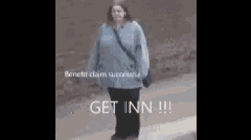 a woman in a blue jacket and black pants is walking down the street .