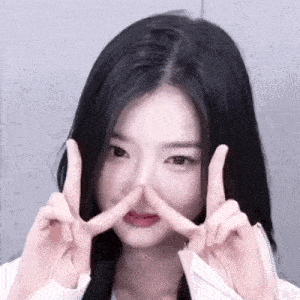 a close up of a woman making a peace sign with her fingers on her nose .