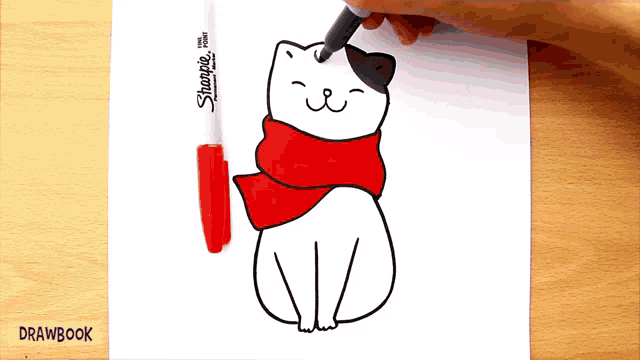 a person is drawing a cat wearing a red scarf with a marker that says sharpie