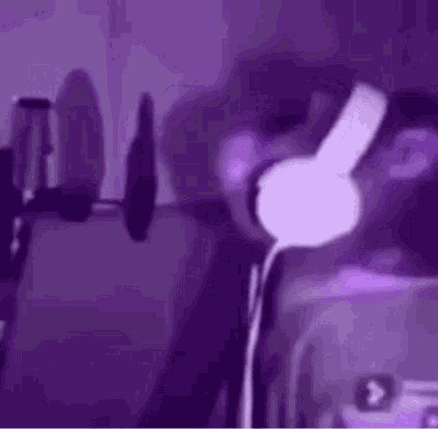 a person wearing headphones is standing in front of a microphone in a dark room .