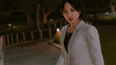 a woman in a white suit is standing in a park