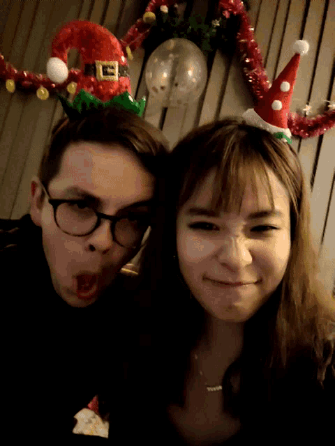 a man and a woman are posing for a picture and the man is wearing a santa hat
