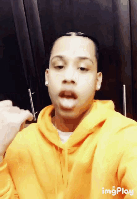 a man wearing a yellow hoodie is taking a selfie
