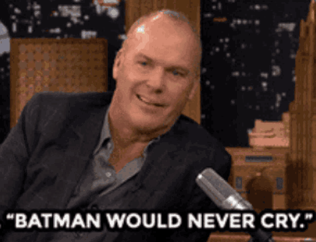 a bald man in a suit says " batman would never cry "