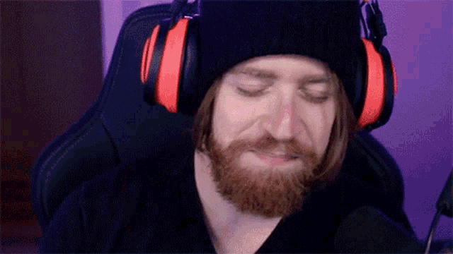 a man with a beard is wearing headphones and a hat .