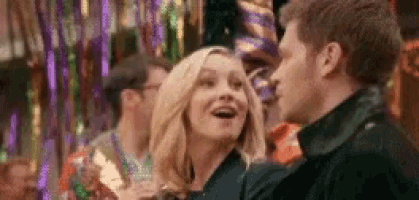 a man and a woman are standing next to each other at a party and smiling .