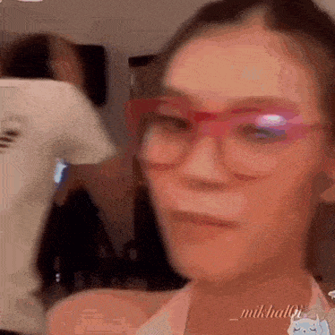 a woman wearing glasses and a white shirt is looking at the camera .