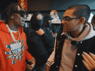 a man wearing a red hoodie with the word splash on it talks to another man