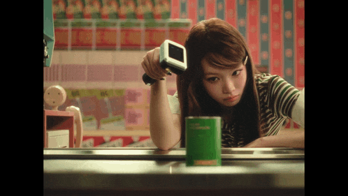 a girl looking at herself in a mirror while holding a small device