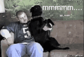 a man with the number 5 on his shirt is sitting on a couch next to a dog