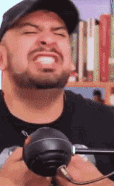 a man with a beard is wearing a black hat and holding a microphone