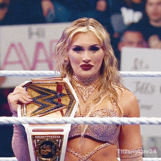 a woman in a wrestling ring holding a championship belt with the word titan on it